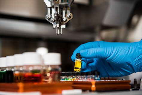 Gloved hand holding sample of liquid